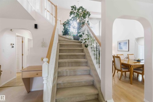 A carpeted staircase with white railings and a wooden handrail leads to the upper level - #1 Colonial Close, Beaumont, AB - Indoor Photo Showing Other Room