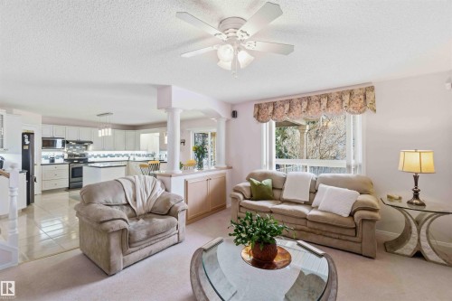 Spacious Family Rm area featuring light-colored carpeting, a ceiling fan, and a large window providing views to the outside - #1 Colonial Close, Beaumont, AB - Indoor Photo Showing Living Room