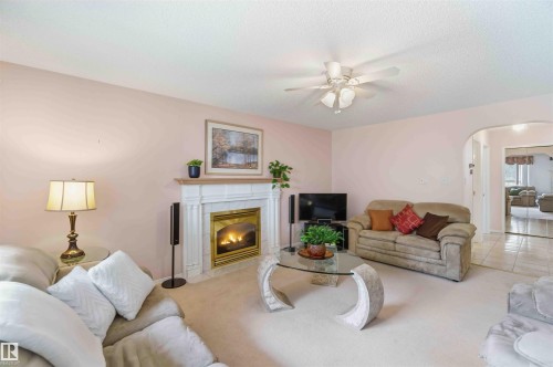 Family room featuring a fireplace with a decorative mantel, carpeted flooring, and a ceiling fan - #1 Colonial Close, Beaumont, AB - Indoor Photo Showing Living Room With Fireplace