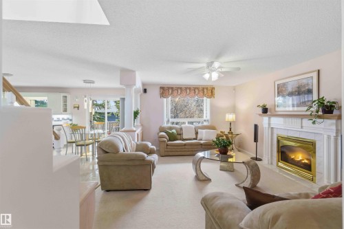 The property features a Family Rm area with a fireplace, a large window, and light-colored carpeting - #1 Colonial Close, Beaumont, AB - Indoor Photo Showing Living Room With Fireplace