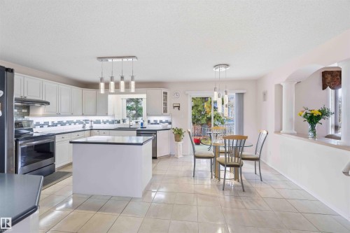 The kitchen features white cabinetry, a kitchen island, and a tiled backsplash - #1 Colonial Close, Beaumont, AB - Indoor Photo Showing Other Room