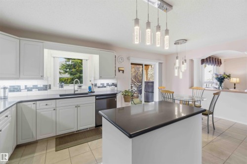 The kitchen features white cabinetry, dark countertops, and a tiled backsplash - #1 Colonial Close, Beaumont, AB - Indoor Photo Showing Kitchen