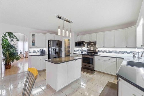 The kitchen features white cabinetry, dark countertops, and tile flooring - #1 Colonial Close, Beaumont, AB - Indoor Photo Showing Kitchen