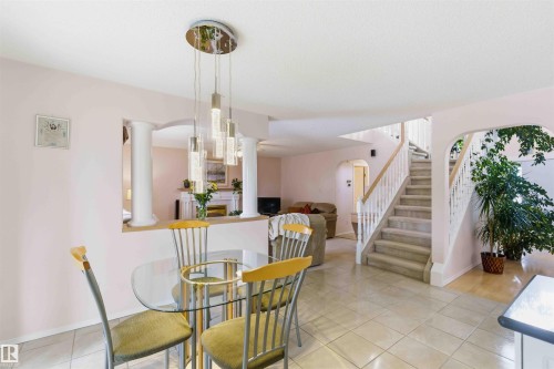 The property features a staircase with carpeted treads and white railings, and tile flooring throughout the main living area - #1 Colonial Close, Beaumont, AB - Indoor Photo Showing Dining Room