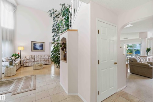 The entryway features tiled flooring, leading to a living area with hardwood floors, high ceilings, and tall windows - #1 Colonial Close, Beaumont, AB - Indoor