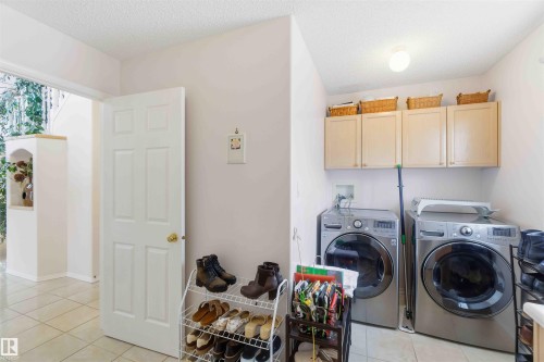 Dedicated laundry area featuring modern appliances and upper cabinetry with storage baskets - #1 Colonial Close, Beaumont, AB - Indoor Photo Showing Laundry Room