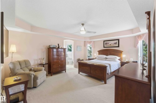 Spacious room featuring light-colored carpet, a tray ceiling, and windows providing natural light - #1 Colonial Close, Beaumont, AB - Indoor Photo Showing Bedroom