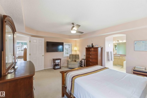 The bedroom features a ceiling fan, carpeted flooring, and a window providing natural light - #1 Colonial Close, Beaumont, AB - Indoor Photo Showing Bedroom