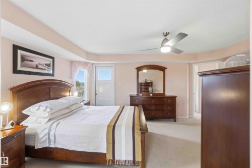 A bedroom featuring light-colored walls, a ceiling fan with integrated lighting, and a white door with a window providing outdoor views - #1 Colonial Close, Beaumont, AB - Indoor Photo Showing Bedroom