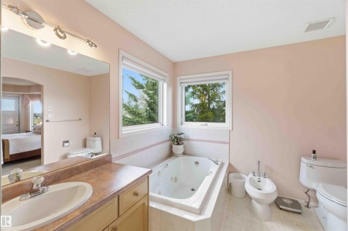 Bathroom featuring a vanity with a sink, a built-in jetted tub, and windows providing natural light - #1 Colonial Close, Beaumont, AB - Indoor Photo Showing Bathroom