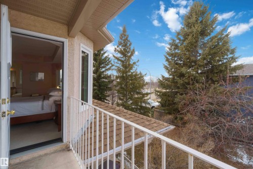 This property features a balcony with a white railing, offering views of mature trees and a residential area - #1 Colonial Close, Beaumont, AB - Outdoor With Balcony With Exterior