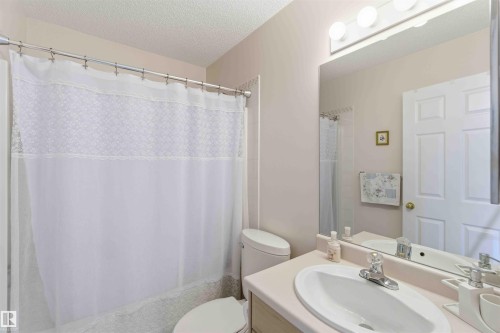 Bathroom featuring a vanity with an oval sink, a toilet, and a shower with a white shower curtain - #1 Colonial Close, Beaumont, AB - Indoor Photo Showing Bathroom