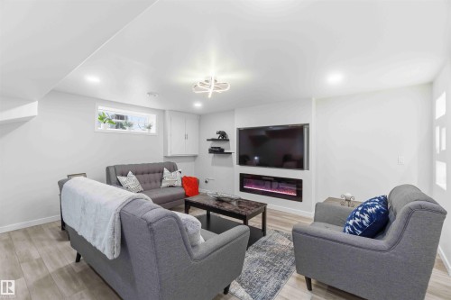 Rec Rm area featuring light wood-style flooring, recessed lighting, and a modern wall-mounted fireplace - #1 Colonial Close, Beaumont, AB - Indoor With Fireplace