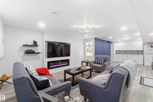 Rec Rm area featuring a wall-mounted electric fireplace, recessed lighting, and light wood-tone flooring - #1 Colonial Close, Beaumont, AB - Indoor Photo Showing Living Room With Fireplace