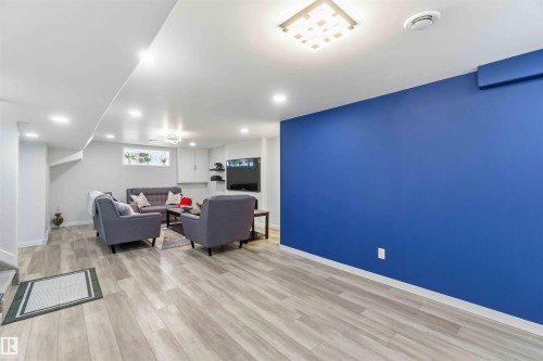 Spacious recreational area featuring light-toned flooring, recessed lighting, and a vibrant accent wall - #1 Colonial Close, Beaumont, AB - Indoor