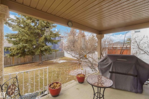 The property features a covered patio with a textured ceiling, overlooking a fenced yard with a mature evergreen tree - #1 Colonial Close, Beaumont, AB - Outdoor With Deck Patio Veranda With Exterior