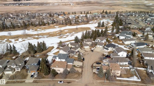 Aerial view of the neighborhood showcasing residential properties and a nearby open field with patches of snow - #1 Colonial Close, Beaumont, AB - Outdoor With View