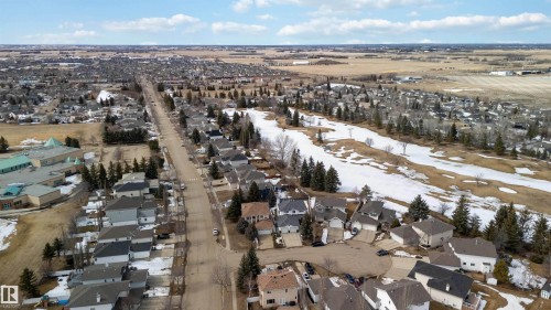 Aerial view showcasing the residential street, nearby golf course, and surrounding community - #1 Colonial Close, Beaumont, AB - Outdoor With View