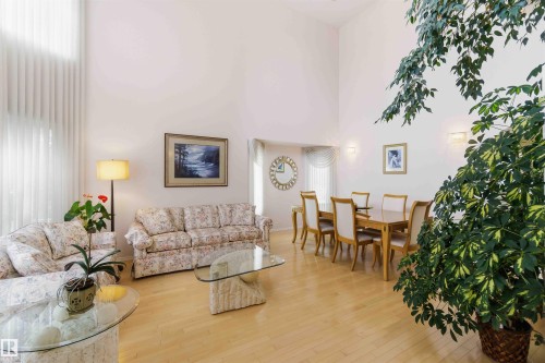 Spacious living area featuring high ceilings, light hardwood floors, and vertical window blinds - #1 Colonial Close, Beaumont, AB - Indoor Photo Showing Living Room