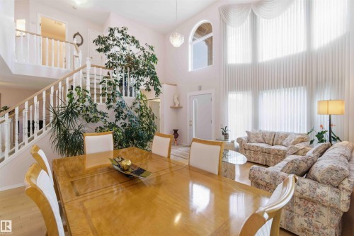 The main living area of the property features a high ceiling, a grand staircase with white railings, and large windows that extend to the ceiling - #1 Colonial Close, Beaumont, AB - Indoor Photo Showing Other Room