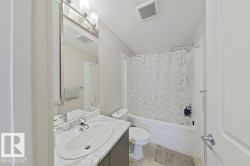 Bathroom featuring a vanity with a white countertop and undermount sink, brushed nickel faucet, wall-mounted mirror, and a full bathtub with a shower - 