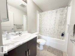 Modern bathroom featuring a single vanity with a white countertop and dark wood-finish cabinetry - 