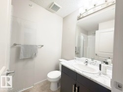 Bathroom featuring a white marble-patterned countertop, dark wood-finish vanity with chrome hardware, an oval undermount sink, and a framed mirror with a four-light fixture - 