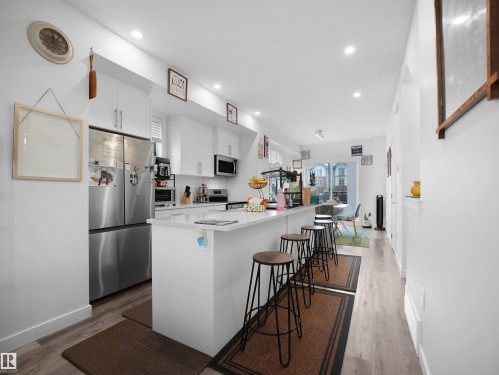 The kitchen features white cabinetry, stainless steel appliances, and a central island with a light-colored countertop - 64 655 Watt Boulevard, Edmonton, AB - Indoor Photo Showing Kitchen With Upgraded Kitchen
