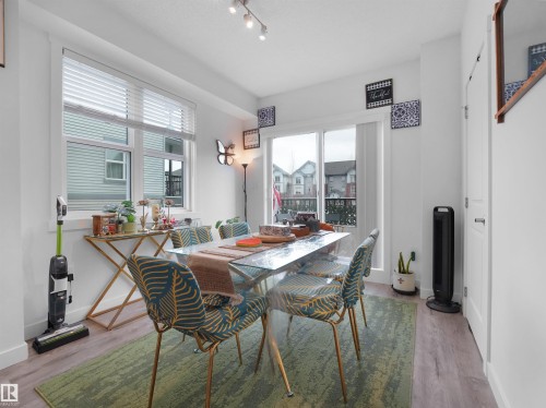 The dining area features light-toned flooring, a light fixture on the ceiling, and glass doors leading to a balcony - 64 655 Watt Boulevard, Edmonton, AB - Indoor Photo Showing Dining Room