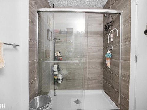 The bathroom features a shower with sliding glass doors, a white shower base, and light brown tiled walls - 64 655 Watt Boulevard, Edmonton, AB - Indoor Photo Showing Bathroom