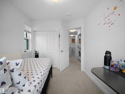 This room features light-colored carpeting, a window with blinds, and white bi-fold closet doors - 64 655 Watt Boulevard, Edmonton, AB - Indoor Photo Showing Bedroom