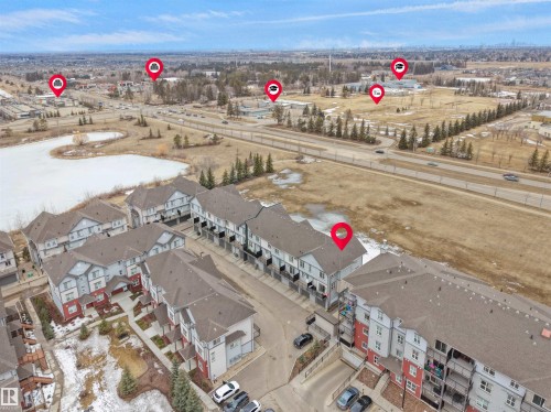 Aerial view showcasing the property within a community of townhouses and apartments, adjacent to a body of water - 64 655 Watt Boulevard, Edmonton, AB - Outdoor With View