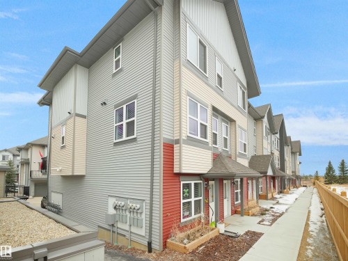 The property features a multi-story exterior with horizontal siding in varying shades, complemented by white window frames - 64 655 Watt Boulevard, Edmonton, AB - Outdoor