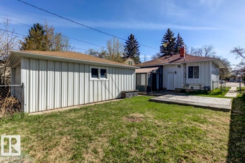 Fenced backyard featuring a detached garage with white siding and a brown shingle roof, a gravel patio area, and an enclosed porch - 9602 90 Street, Edmonton, AB - Outdoor