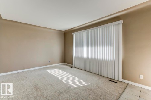 Spacious room with neutral-toned walls, light-colored carpeting, a large vertical blind window treatment, a ceiling with recessed lighting, and white baseboards - 9602 90 Street, Edmonton, AB - Indoor Photo Showing Other Room