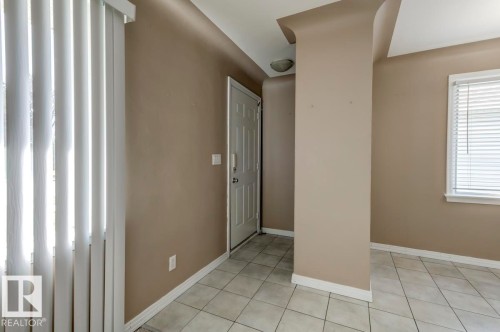 Foyer entry featuring ceramic tile flooring, a paneled entry door, a window with horizontal blinds, and a built-in ceiling light fixture - 9602 90 Street, Edmonton, AB - Indoor Photo Showing Other Room