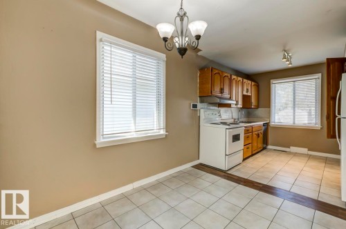 Kitchen with light-toned tiled flooring and wood-finish accent strip - 9602 90 Street, Edmonton, AB - Indoor Photo Showing Kitchen