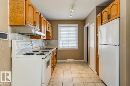 U-shaped kitchen featuring light wood cabinetry, white appliances, and a tiled backsplash - 9602 90 Street, Edmonton, AB - Indoor Photo Showing Kitchen