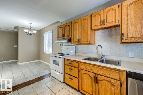 Kitchen featuring wood cabinetry, a dual basin stainless steel sink, and a ceramic tile backsplash - 9602 90 Street, Edmonton, AB - Indoor Photo Showing Kitchen With Double Sink