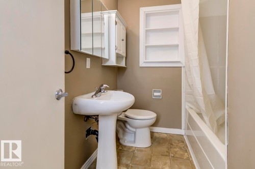 Pedestal sink with chrome fixtures, mirrored medicine cabinet, and built-in wall shelving - 9602 90 Street, Edmonton, AB - Indoor Photo Showing Bathroom