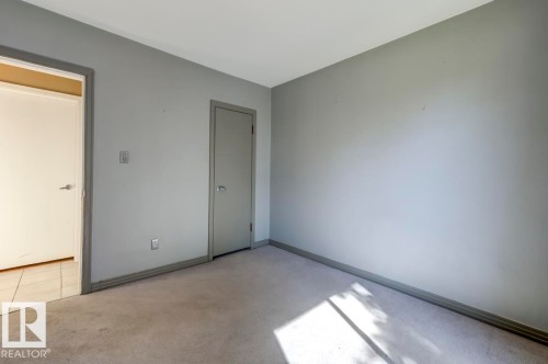 Neutral gray wall paint with contrasting trim, light carpeting, and two doorways providing access to additional spaces - 9602 90 Street, Edmonton, AB - Indoor Photo Showing Other Room
