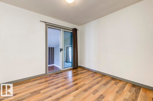 Room featuring wood-finish flooring, white walls, and a sliding glass door - 9602 90 Street, Edmonton, AB - Indoor Photo Showing Other Room