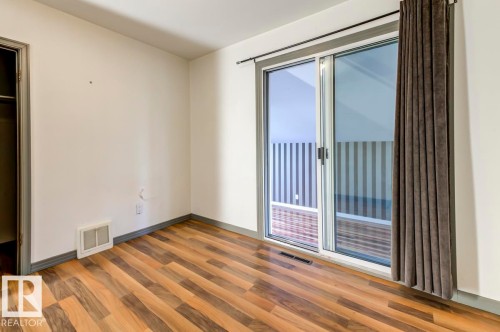 Room featuring wood-finish flooring, a sliding glass door with dark gray trim, and an open closet entry - 9602 90 Street, Edmonton, AB - Indoor Photo Showing Other Room