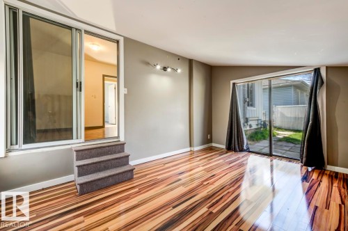 Spacious room featuring wood-finish flooring, neutral-toned walls, and a track lighting fixture - 9602 90 Street, Edmonton, AB -  Photo Showing Other Room
