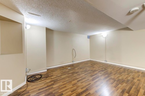 Finished room featuring wood-finish flooring, recessed wall niche, and warm neutral wall color - 9602 90 Street, Edmonton, AB - Indoor Photo Showing Other Room