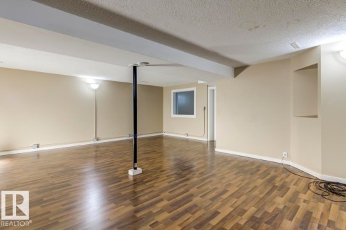 Spacious room featuring wood-finish flooring, neutral wall paint, and recessed ceiling lighting - 9602 90 Street, Edmonton, AB - Indoor