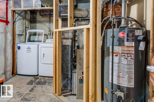 Utility area featuring a top-load washing machine, front-load dryer, water heater, and furnace - 9602 90 Street, Edmonton, AB - Indoor Photo Showing Basement