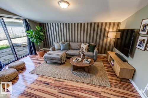 Spacious living area featuring high-gloss wood-finish flooring and direct access to an outdoor patio - 9602 90 Street, Edmonton, AB - Indoor Photo Showing Living Room