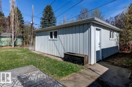 Detached outbuilding with corrugated metal siding, white entry door, two windows, and a concrete perimeter - 9602 90 Street, Edmonton, AB - Outdoor