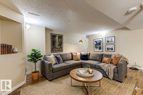 Spacious entertainment area featuring wood-finish flooring, recessed wall niche, and built-in ceiling lighting - 9602 90 Street, Edmonton, AB - Indoor Photo Showing Living Room